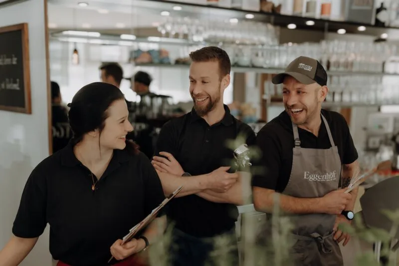 Lachendes Team des Eggen - Café Bistro in Reith im Alpbachtal, das gemeinsam in entspannter Atmosphäre arbeitet.