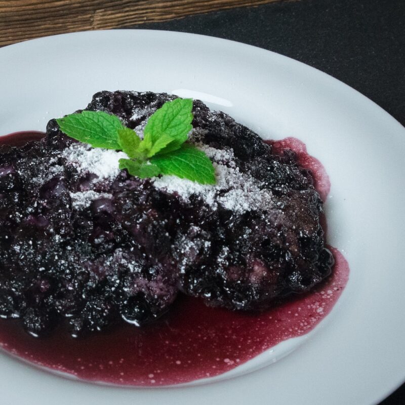 Moosbeernocken nach Tiroler Rezept auf Teller mit Staubzucker und Minze garniert