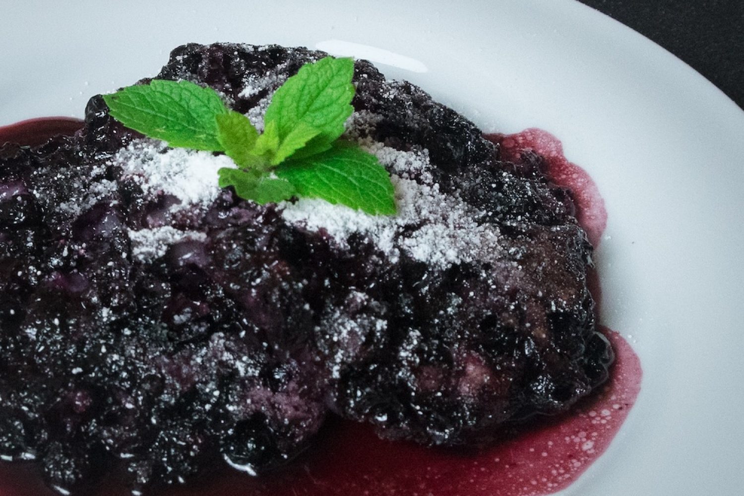 Moosbeernocken nach Tiroler Rezept auf Teller mit Staubzucker und Minze garniert